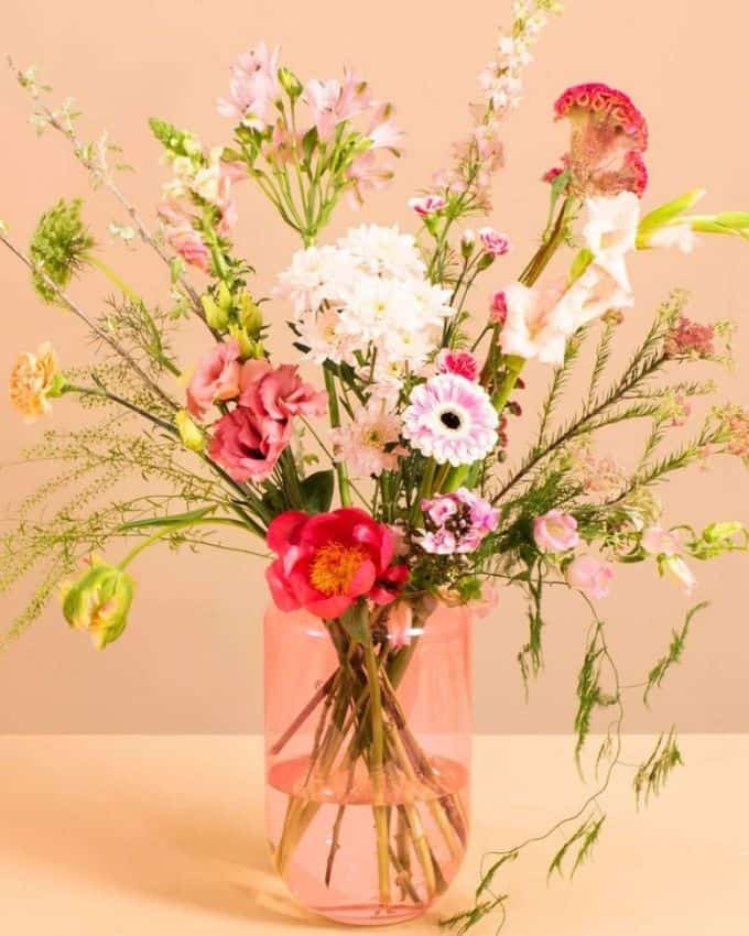 Blumenstrauß mit bunten Blumen in einer klaren rosa Vase
