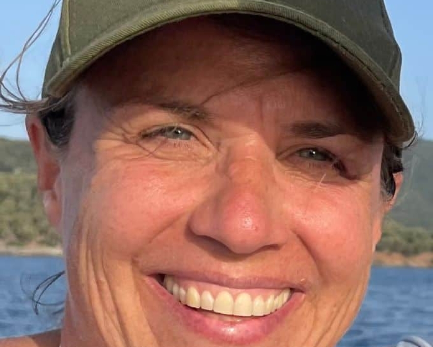 Frau lacht in die Kamera, ist im Urlaub und trägt ein oliv grünes Cap von den New York Yankees