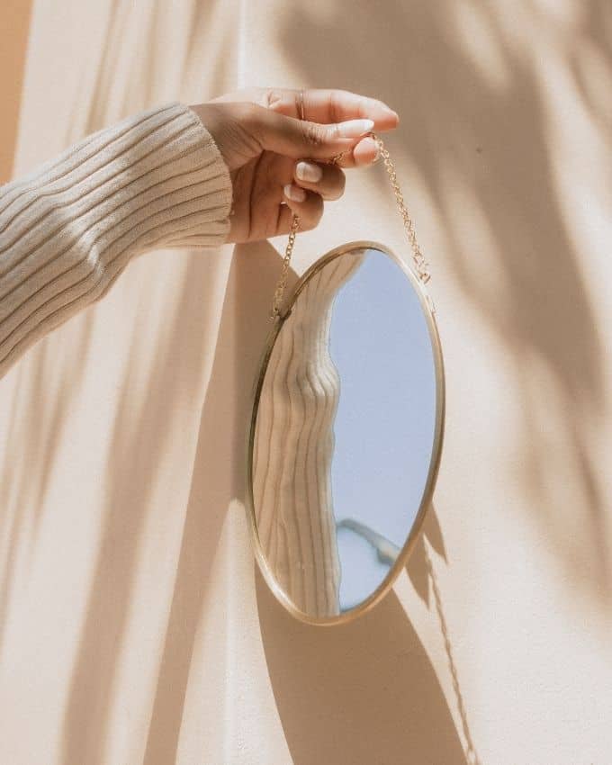 eine Frau hält einen ovalen Spiegel, der an einem Band hängt
