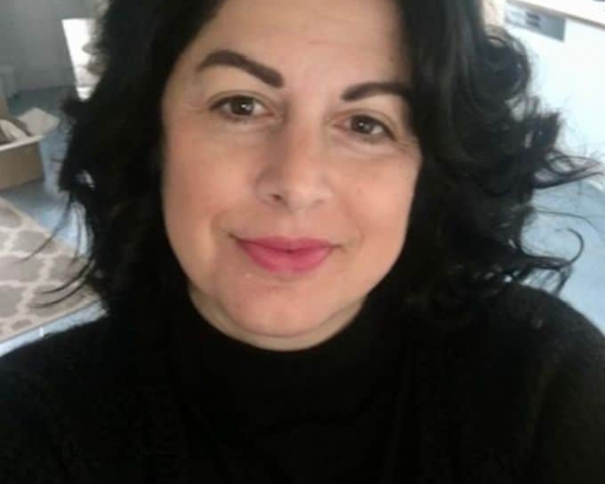 So sieht 45 aus. 45 jährige Frau mit schwarzem welligen Haar und auffallend geformten Augenbrauen und schwarzem Pullover schaut zufrieden in die Kamera.