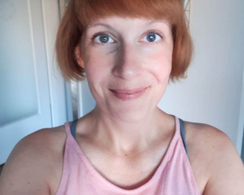 So sieht 46 aus. 46 jährige Frau mit rotem Bob und Pony lächelt in die Kamera. Sie trägt ein rosa Top.