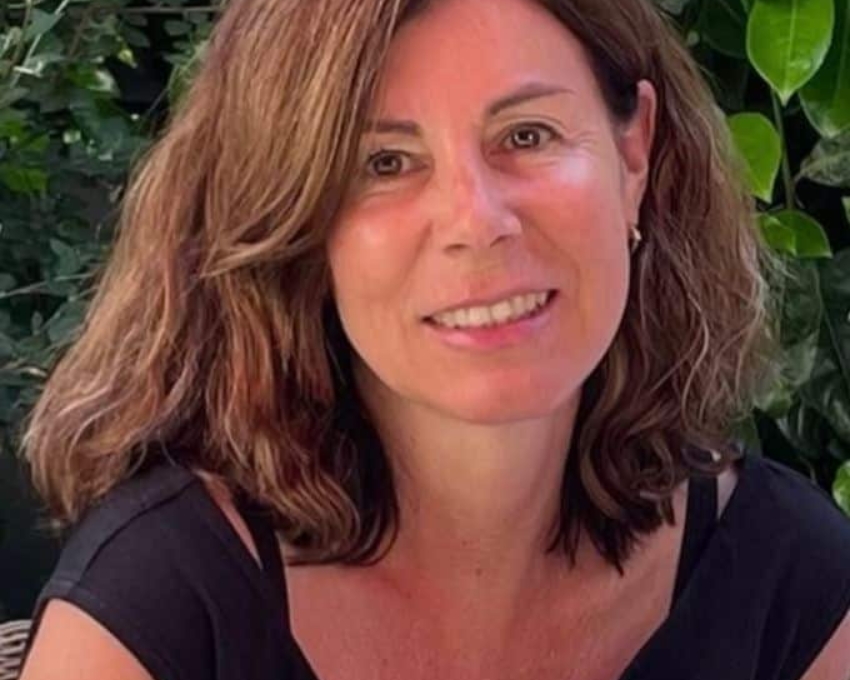 So sieht 53 aus. 53 jährige Frau mit braunem offenen Haar lächelt in die Kamera. Sie trägt ein schwarzes, sommerliches Oberteil.