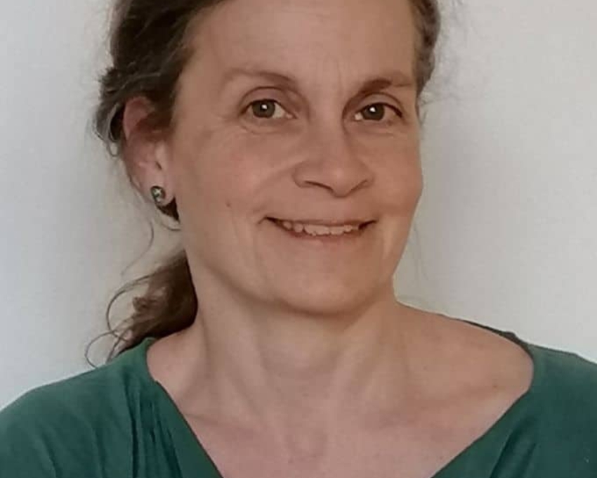 So sieht 55 aus. 55 jährige Frau mit grünem Oberteil lächelt in die Kamera.