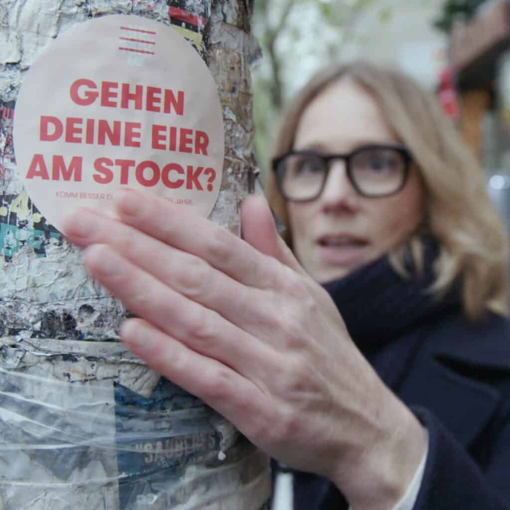 Susanne Liedtke klebt Sticker auf Laternenmast