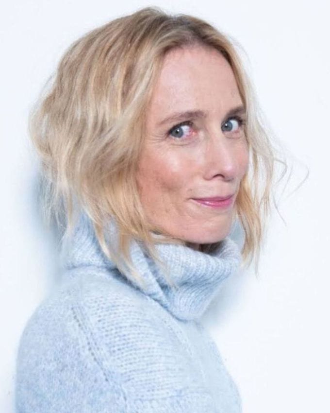 Porträt einer Frau mit blonden Haaren und hellblauem Rollkragen Pullover.