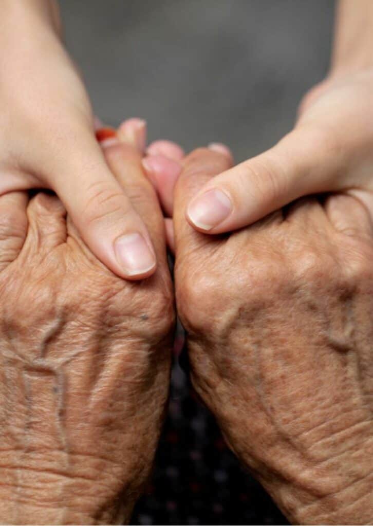 Die beiden Hände Tochter hält die Hände ihrer pflegebedürftigen Mutter