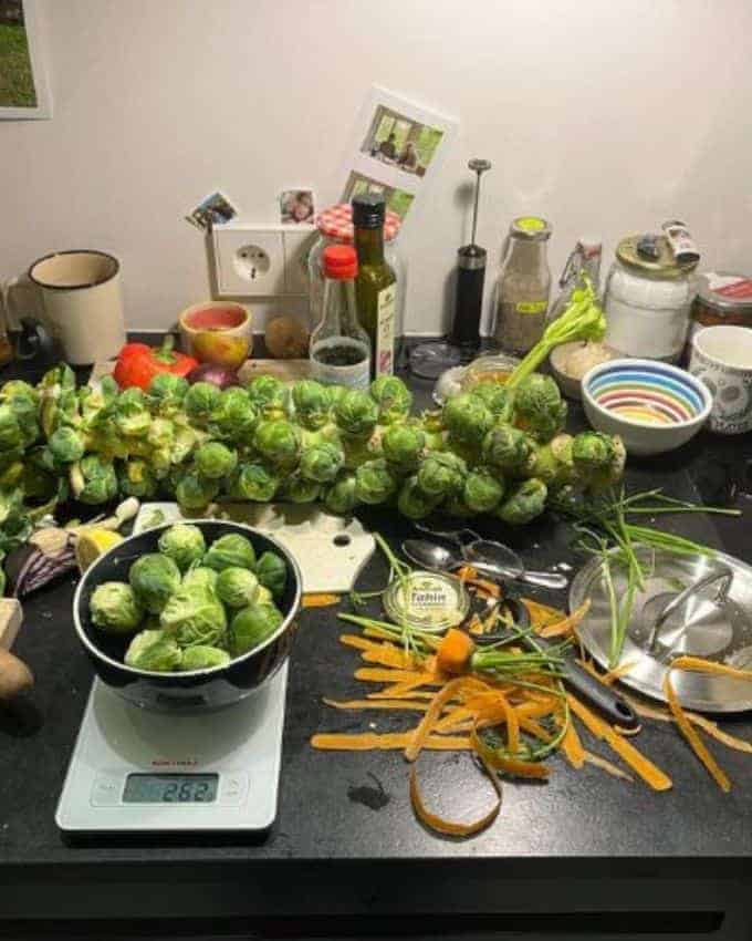 Küchentresen mit geschnittenem Gemüse, Rosenkohl, Karotten, Waage, Küchenutensilien und Saucen