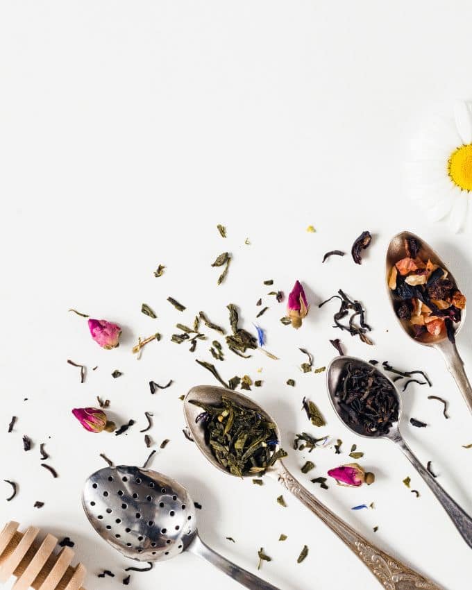 Vier Teelöffel mit getrockneten Tee Blüten.