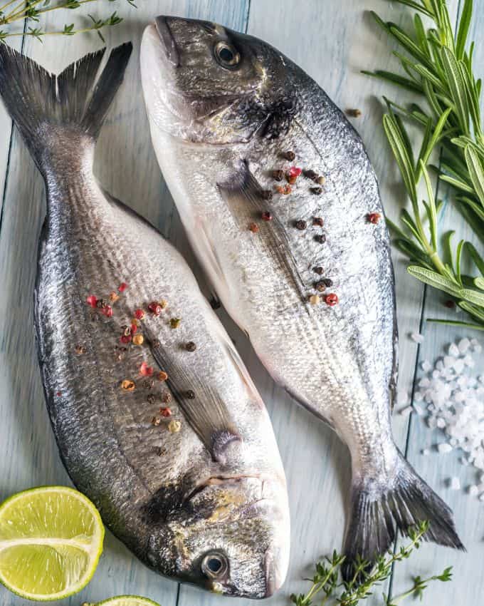 Zwei silberne Fische, Limette, Rosmarin und Pfefferkörner