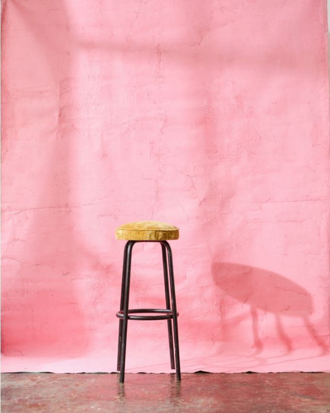 Hocker vor einer rosa Farben Leintuch Wand