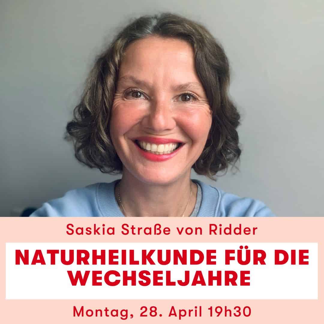 Frau grinsend mit braunen kurzen Haaren, blaues T-Shirt und rotem Lippenstift