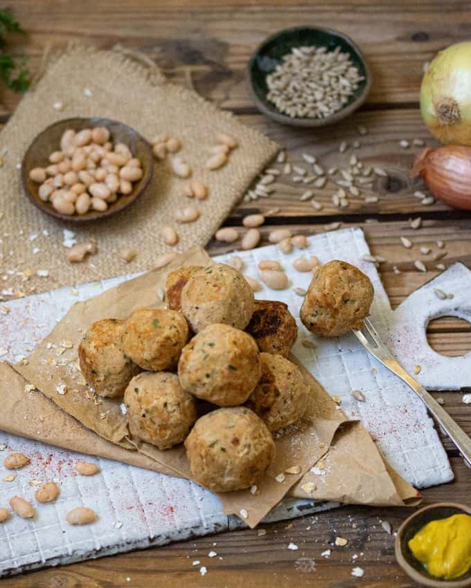 Bohnenbällchen auf einen Holzbrett mit Kernen und Petersilie garniert.