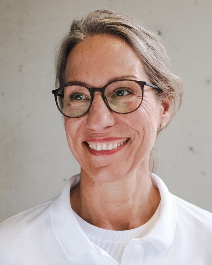Frau mit blonden Haaren, Brille und weißem Kittel