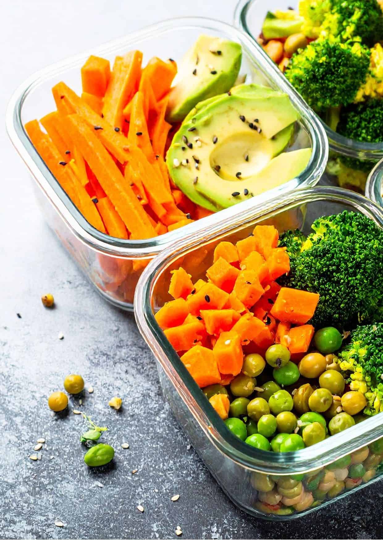 Bunte gesunde Mahlzeit mit Avocado, Karotten, Brokkoli, Erbsen und Süßkartoffeln in Glasbehältern – frische, ballaststoffreiche Ernährung für mehr Energie und Wohlbefinden.