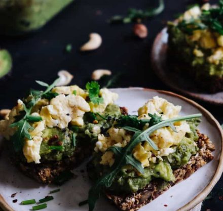 Avocadopüree mit Rührei auf Toasts in einem weißen Teller
