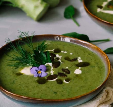 Eine grüne, mit violetten Blumen verzierte Suppenschüssel auf einem Holztisch