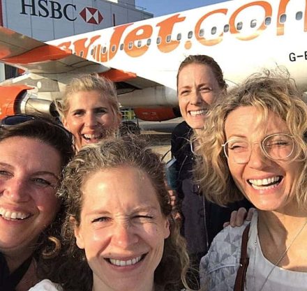 Selfie von vier Köpfe von Frauen vor einen Flugzeug.