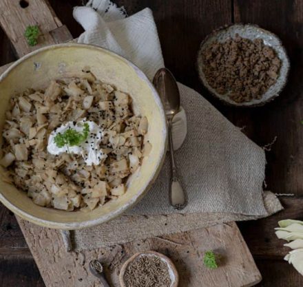 Geschmorter Weißkohl mit veganem Hack in grauer Schale angerichtet und mit frischer Petersilie garniert.