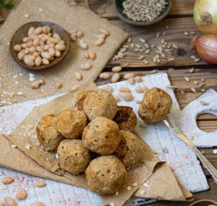 Bohnenbällchen auf einen Holzbrett mit Kernen und Petersilie garniert.