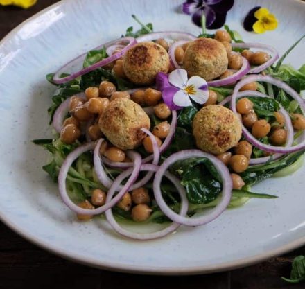 Kichererbsensalat in einer weißen Schale, verziert mit Blumen und Zwiebelringen
