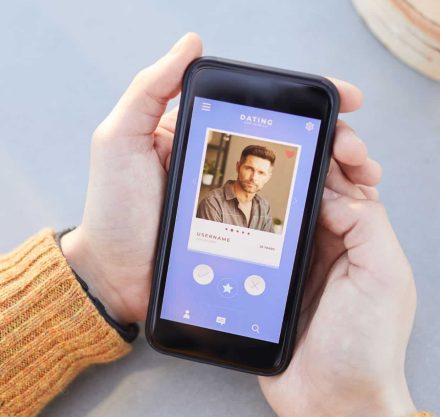 Hände einer Frau, die ein Smartphone nimmt und in eine Online-Dating-App schaut