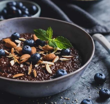Schoko-Frühstücksbowl mit Mandeln, Blaubeeren und Minze auf Schieferplatte