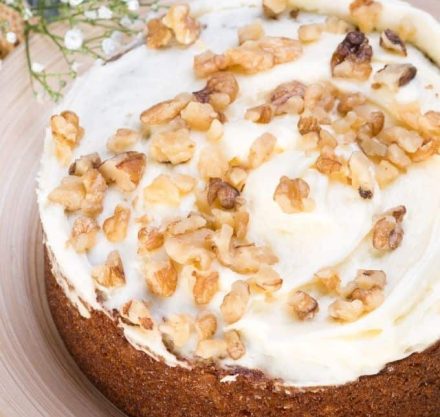 Karottenkuchen mit Frischkäsecreme und Walnüssen neben frischen Blumen