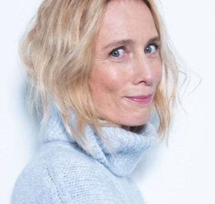 Porträt einer Frau mit blonden Haaren und hellblauem Rollkragen Pullover.