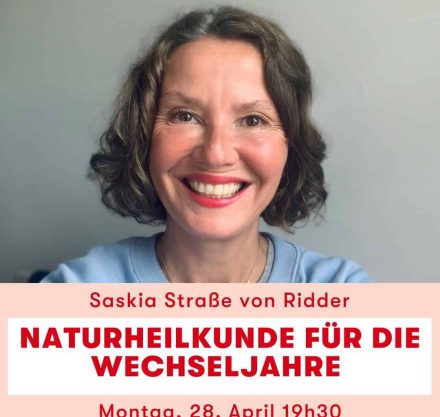 Frau grinsend mit braunen kurzen Haaren, blaues T-Shirt und rotem Lippenstift
