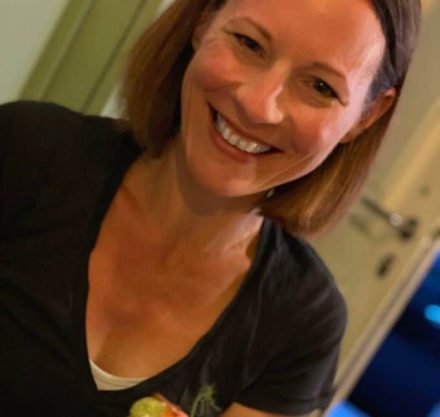 Simone Schlaack lacht in die Kamera, sie hat ein belegtes Brot in der Hand