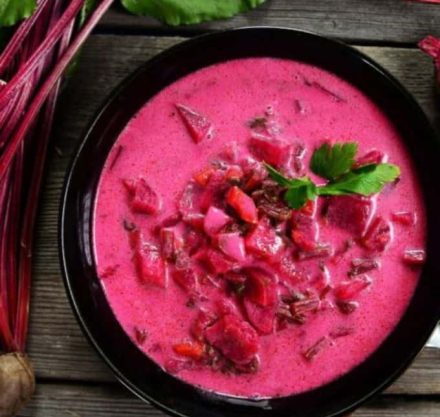Warme Mandel-Rote-Bete-Suppe in schwarzer Schüssel mit frischer Petersilie garniert.