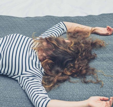 Frau liegt erschöpft auf dem Bett