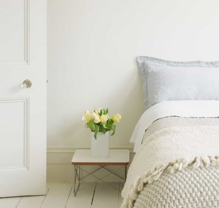 helles Schlafzimmer mit Blumenstrauß und Holzfussboden