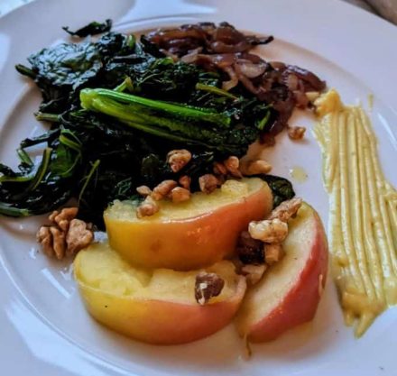 Teller mit warmem Grünkohlsalat, Apfelscheiben, Walnüssen und Zwiebeln